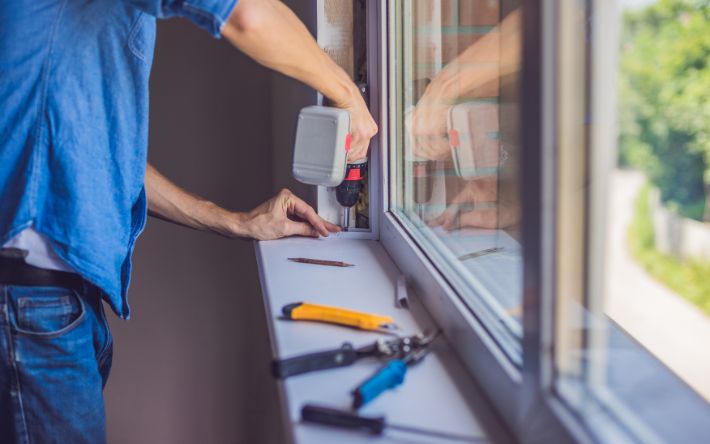 Technician installing a replacement window in a residential home.